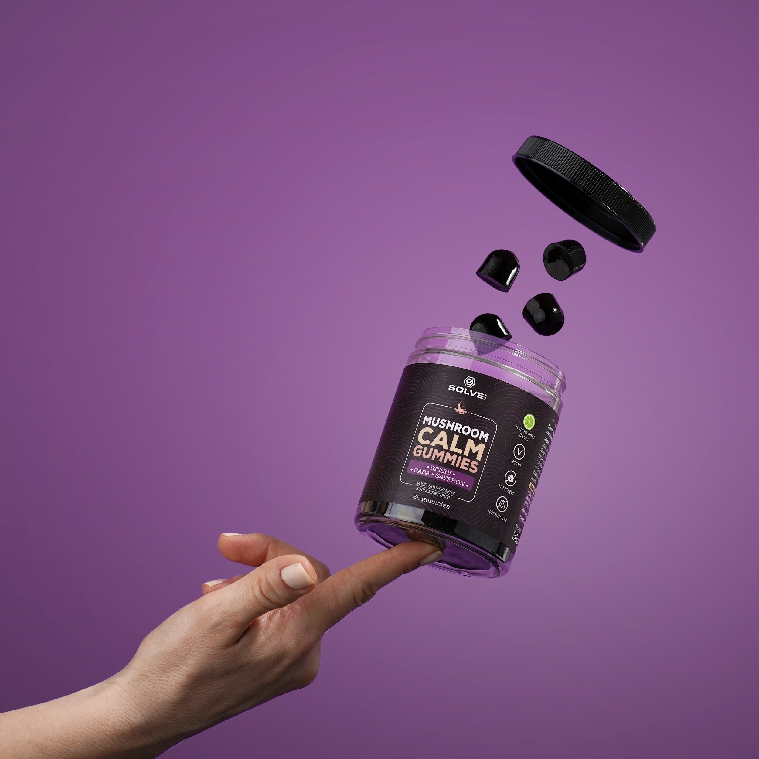 Hand holding a purple supplement container with black caps against a purple background