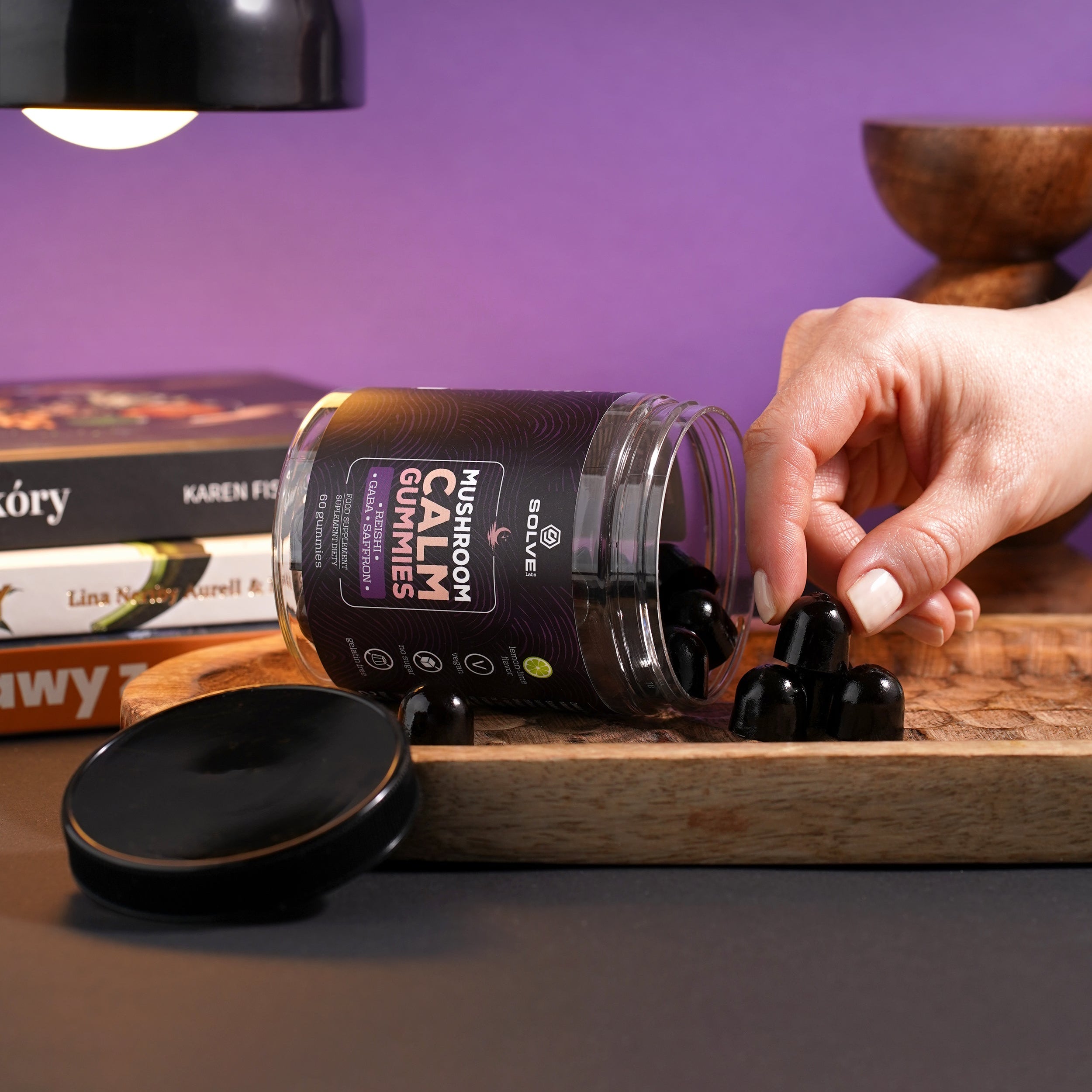 Hand interacting with a jar labeled 'Natures Plus Calm Gummies' on a wooden surface with a purple background.