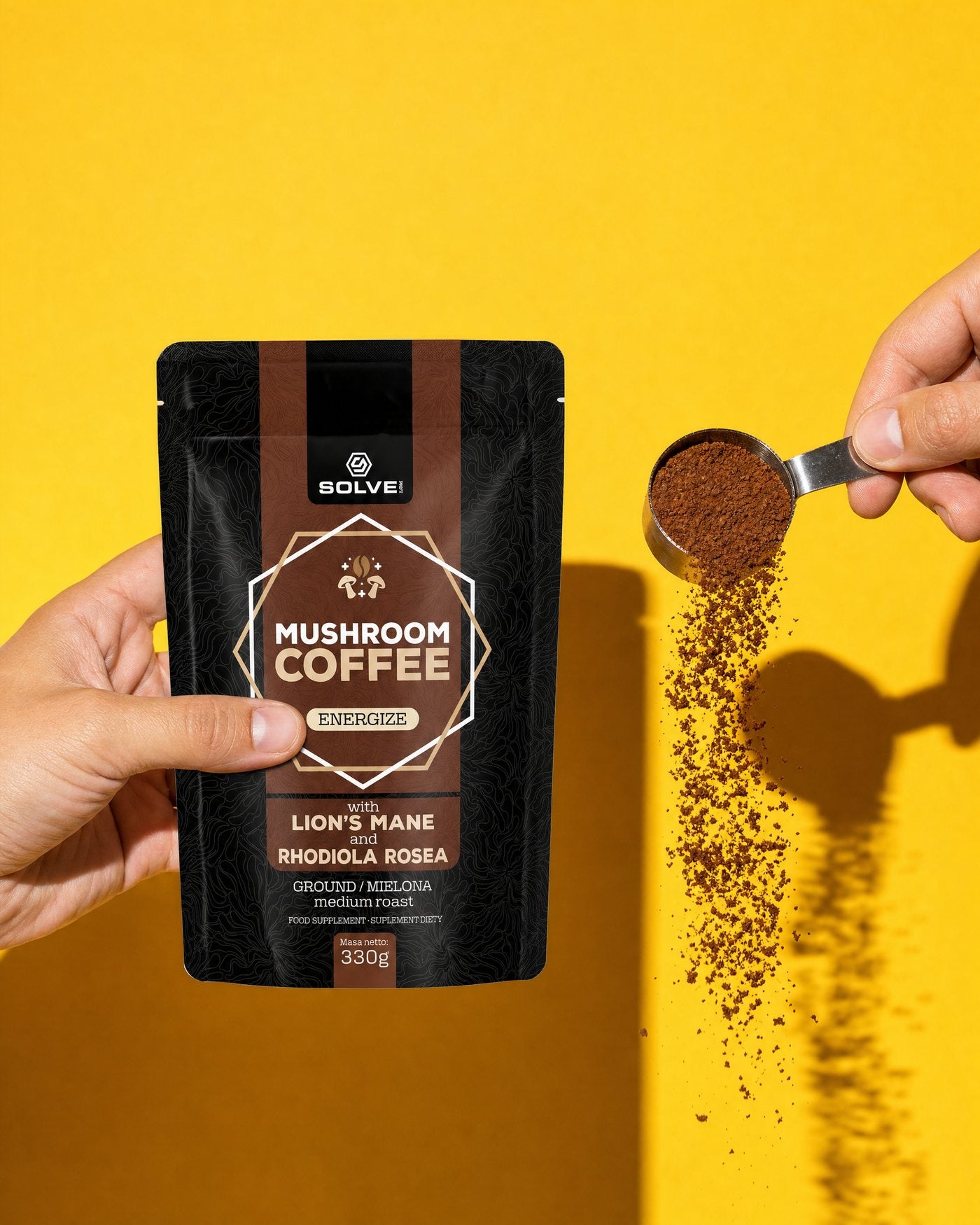 Una mano sostiene la bolsa de café con hongos de Solve Labs mientras otra vuelca un cacito de café molido, sobre un fondo amarillo