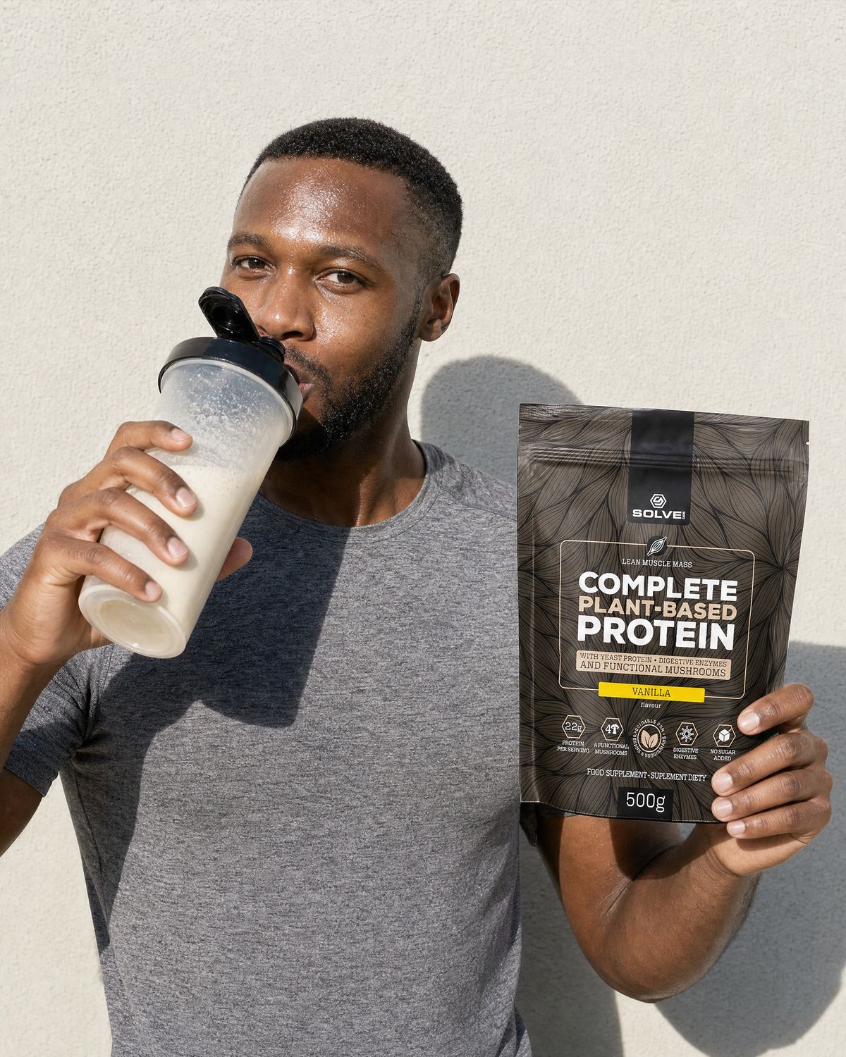 A man drinking a vanilla shake from a shaker, holding up the vanilla pouch