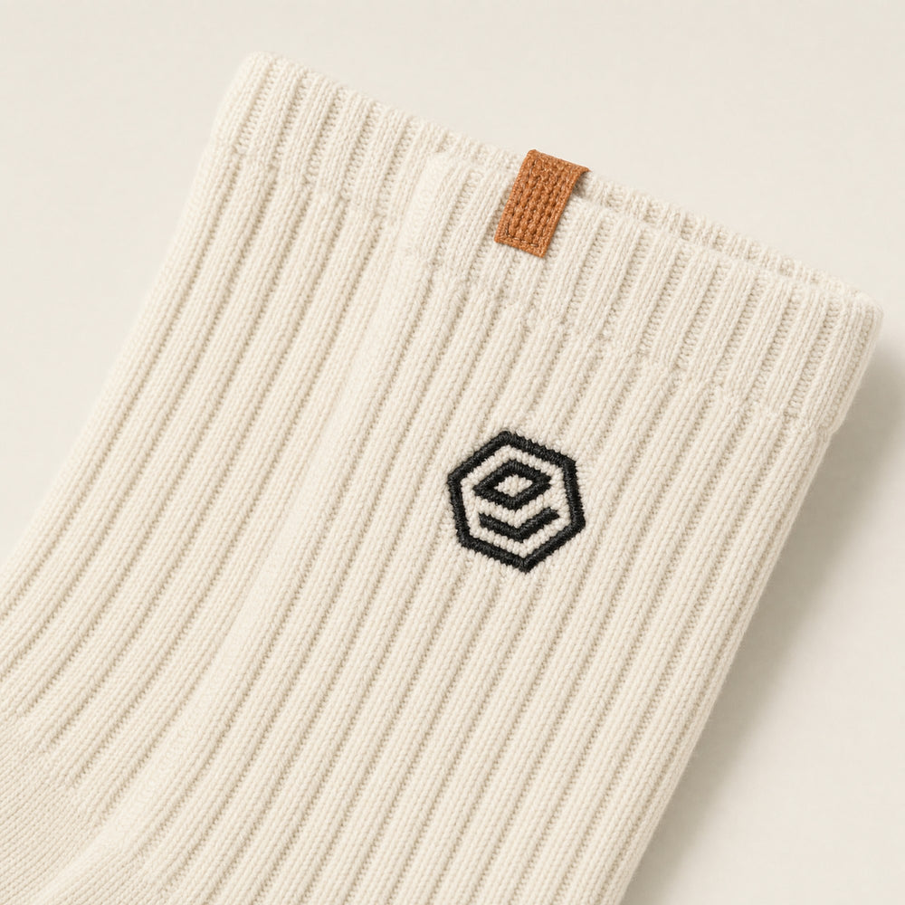 The embroidered hex and orange tab on a bone Hex Sock