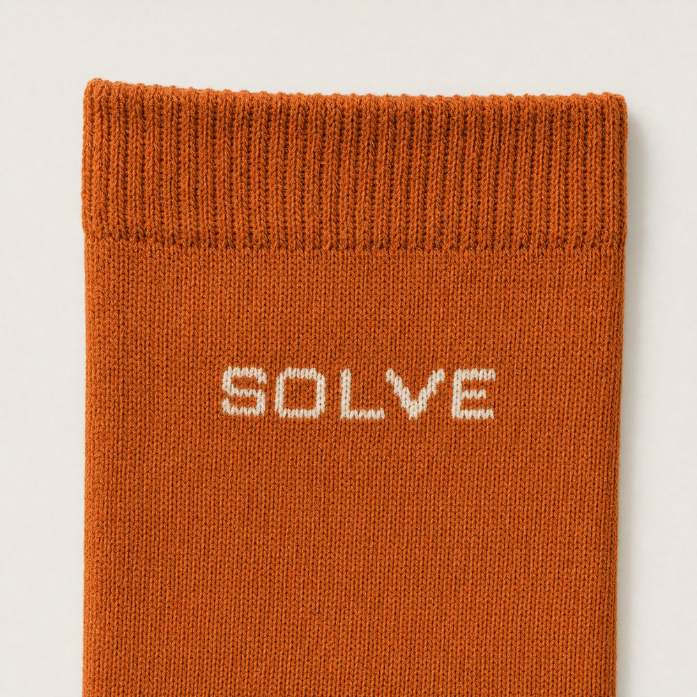 SOLVE knitted into the cuff of an orange crew sock