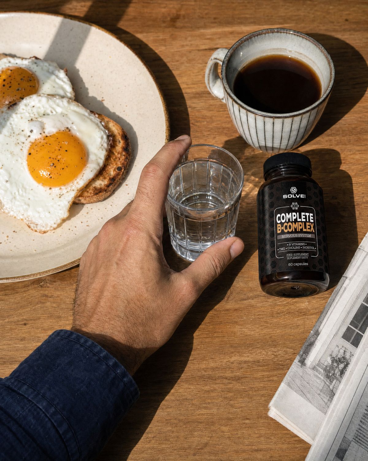 A hand reaching for a glass of water on a breakfast table beside the jar