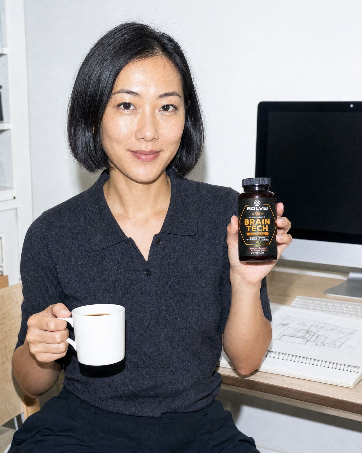 A woman at her desk with a mug of coffee, holding up the jar of Brain Tech