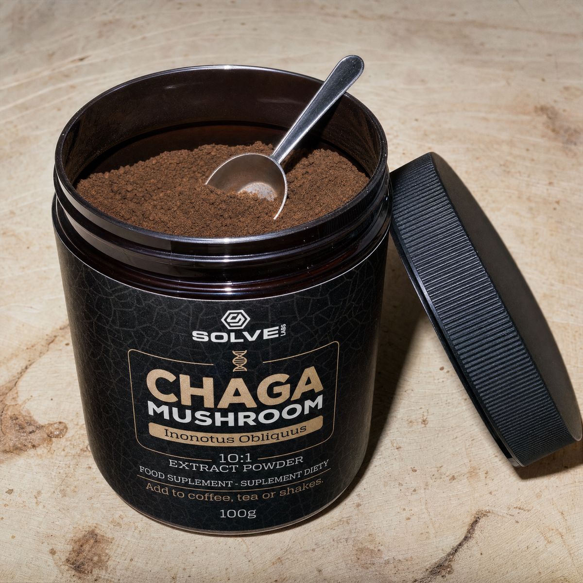 The open jar of chaga powder with a steel spoon in it
