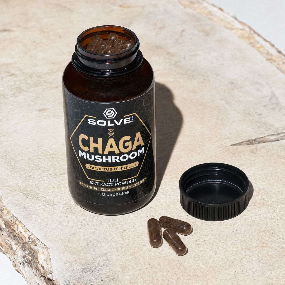 The open jar of Solve Labs Chaga capsules, three capsules beside its cap