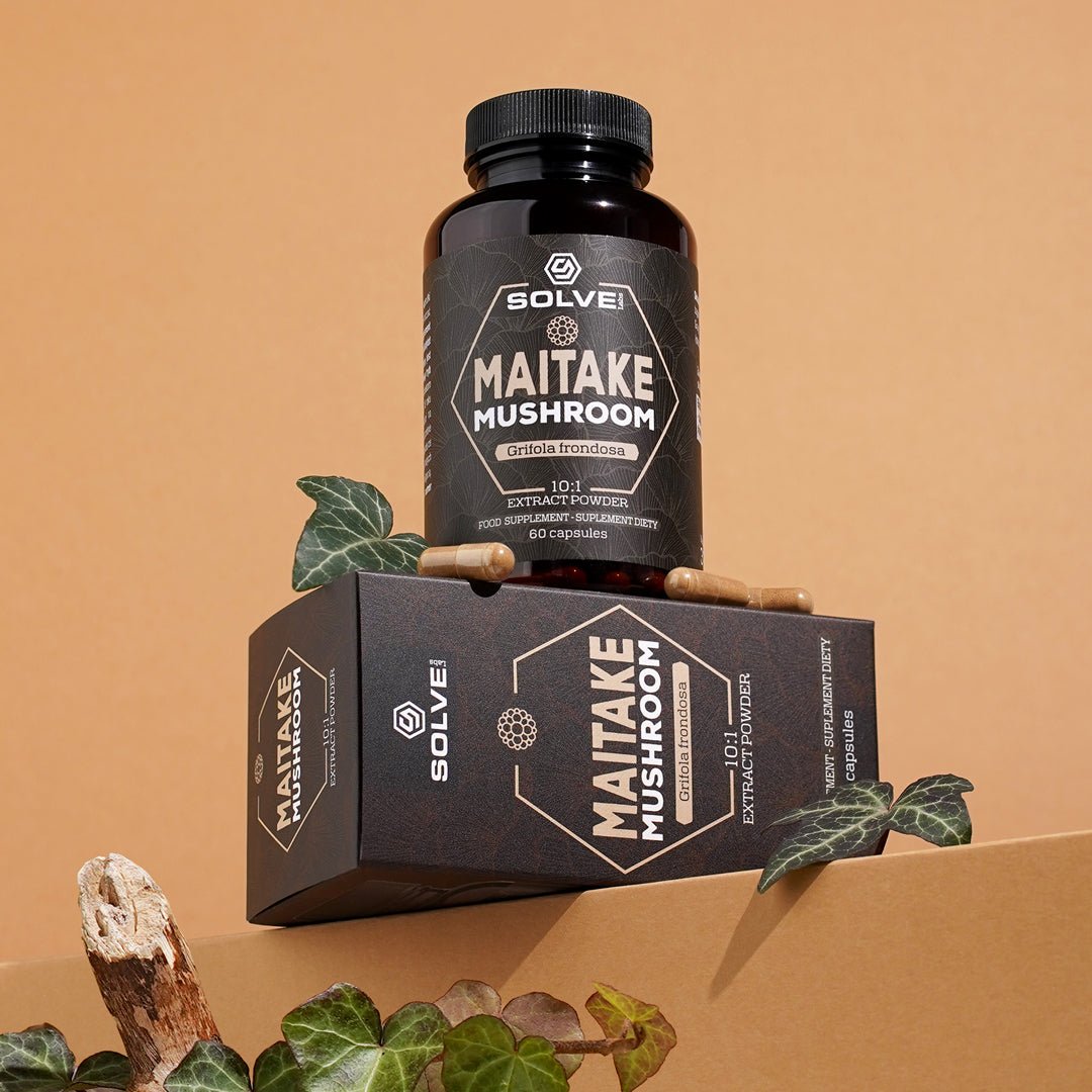 El bote de Solve Labs Maitake en cápsulas sobre su caja, con tres cápsulas al lado y hiedra alrededor, fotografiado en un decorado de papel color tostado