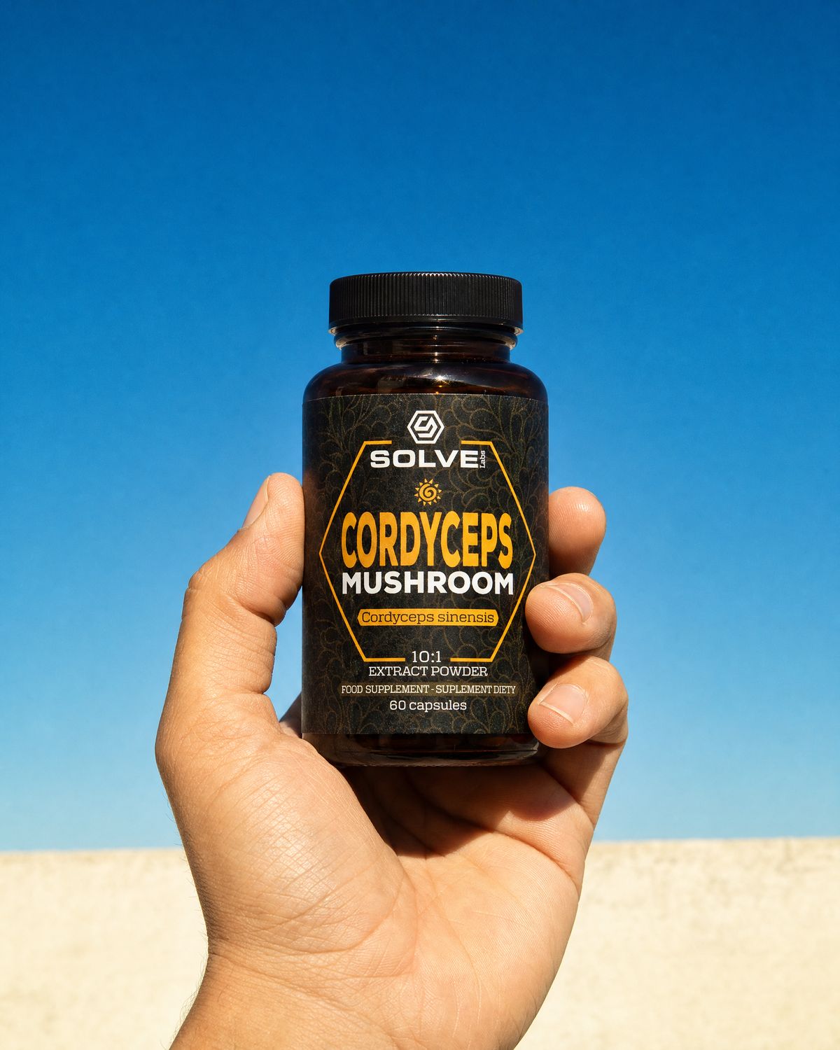 A hand holding up a jar of Solve Labs Cordyceps capsules against a deep blue sky