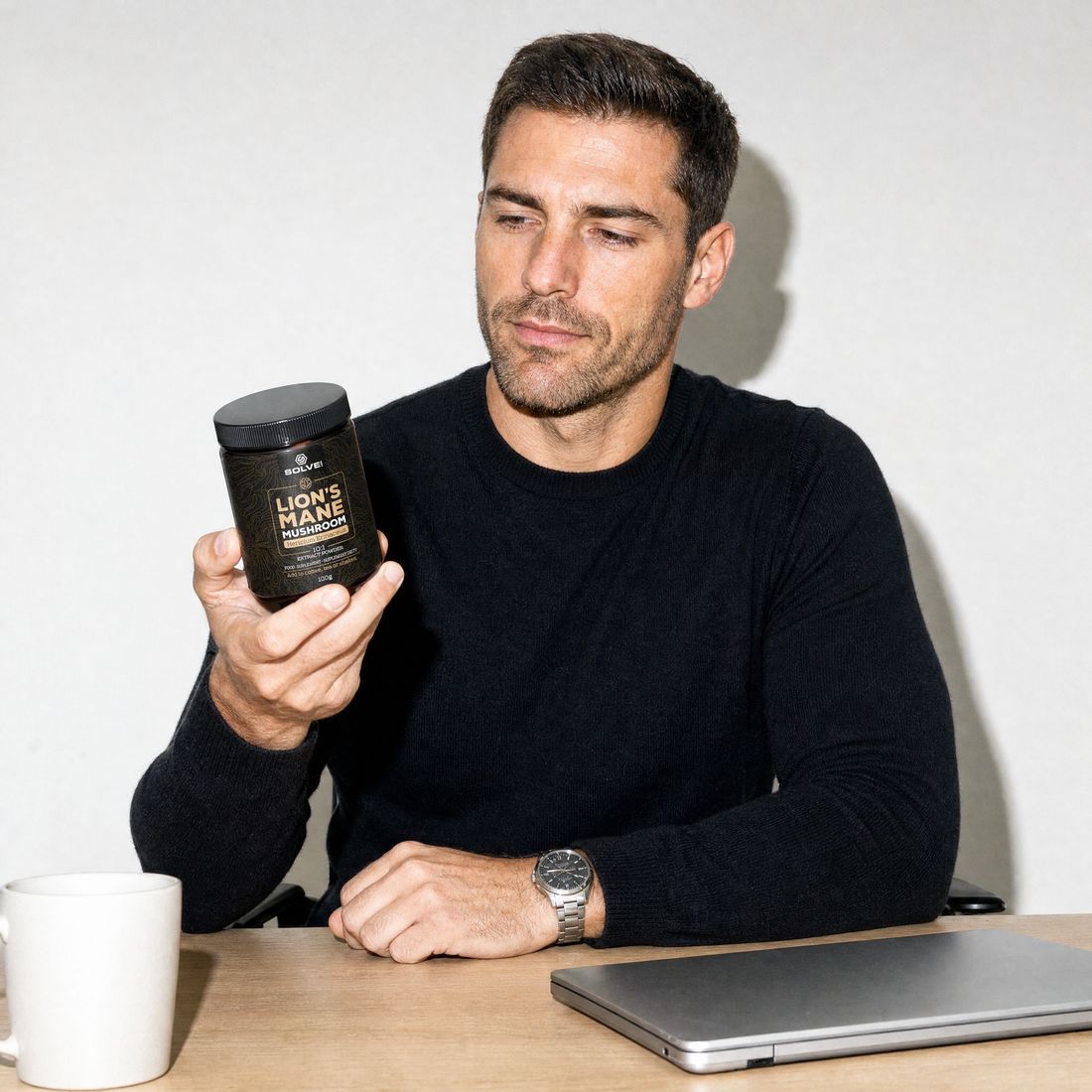 A man at his desk reading the label on a jar of Solve Labs Lion&rsquo;s Mane powder