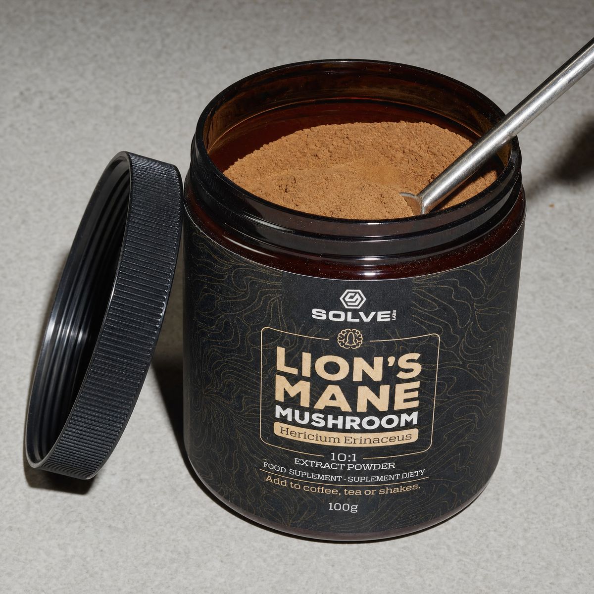 The open jar of lion&rsquo;s mane powder with a steel spoon in it