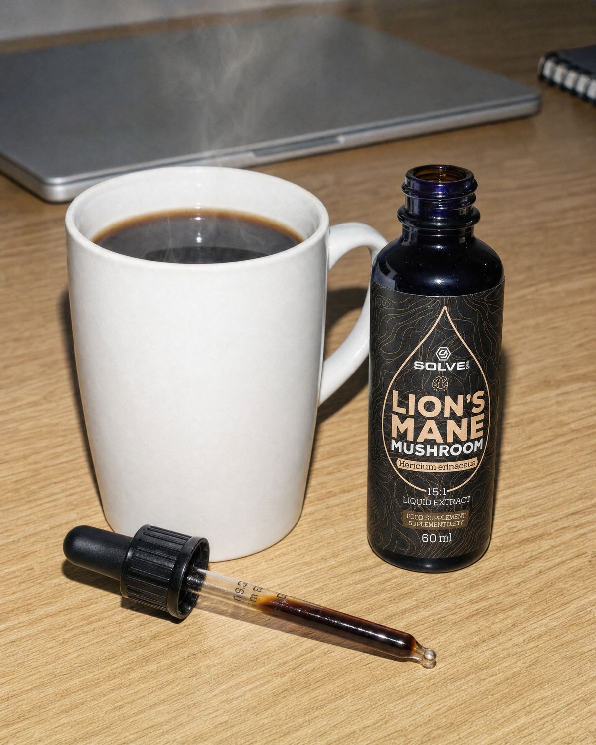 A mug of black coffee on a desk, a dropper of lion&rsquo;s mane extract in front of it, the bottle beside it