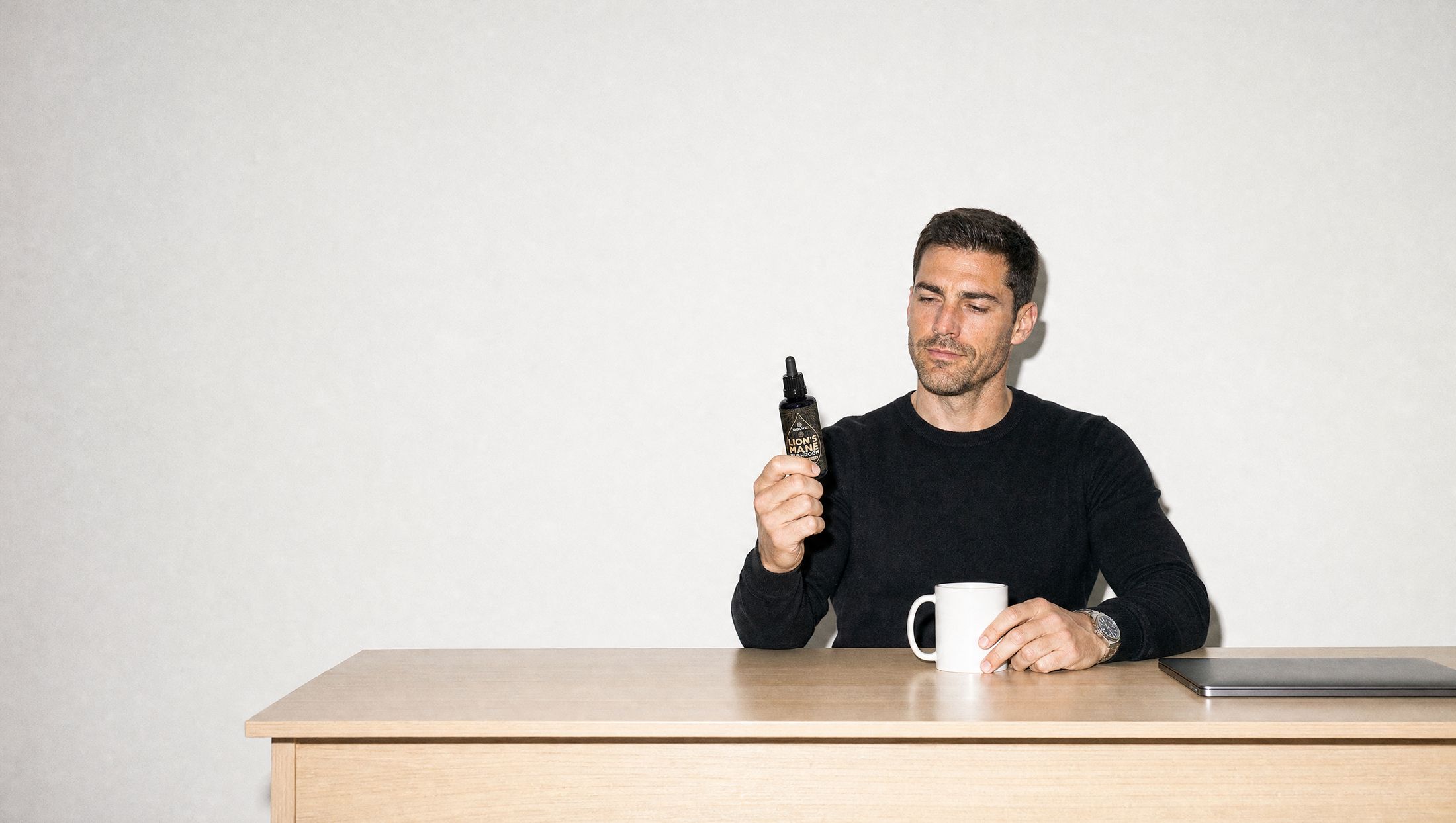 A man at his desk reading the back label of a bottle of Solve Labs Lion&rsquo;s Mane drops