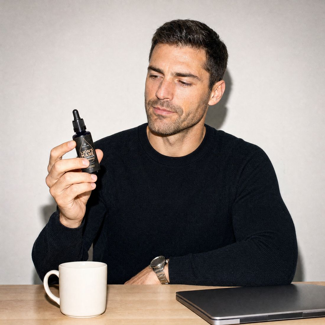 A man at his desk reading the label on a bottle of Solve Labs Lion&rsquo;s Mane drops