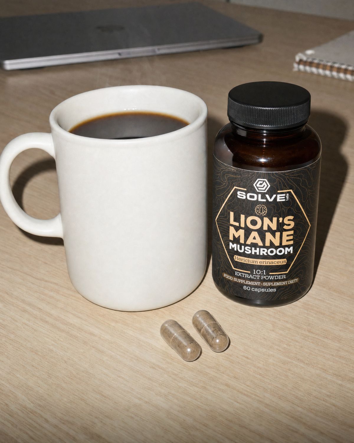 A mug of black coffee on a desk, two lion&rsquo;s mane capsules in front of it, the jar beside it