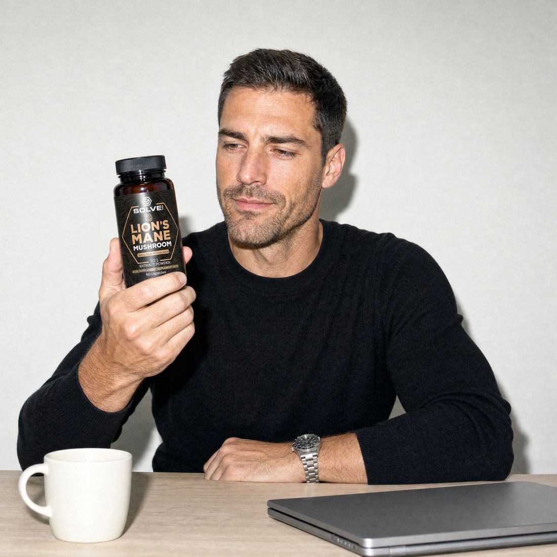 A man at his desk reading the label on a jar of Solve Labs Lion&rsquo;s Mane capsules