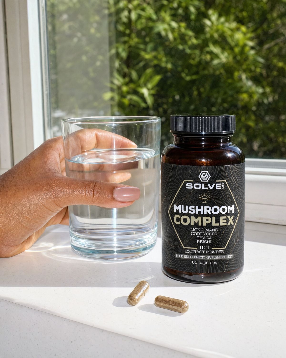 Two Mushroom Complex capsules on a kitchen worktop beside a glass of water and the jar