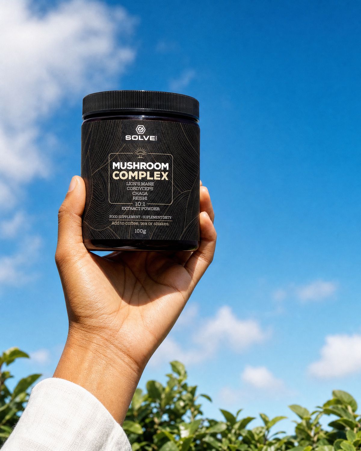 A hand holding up a jar of Solve Labs Mushroom Complex powder against a blue summer sky