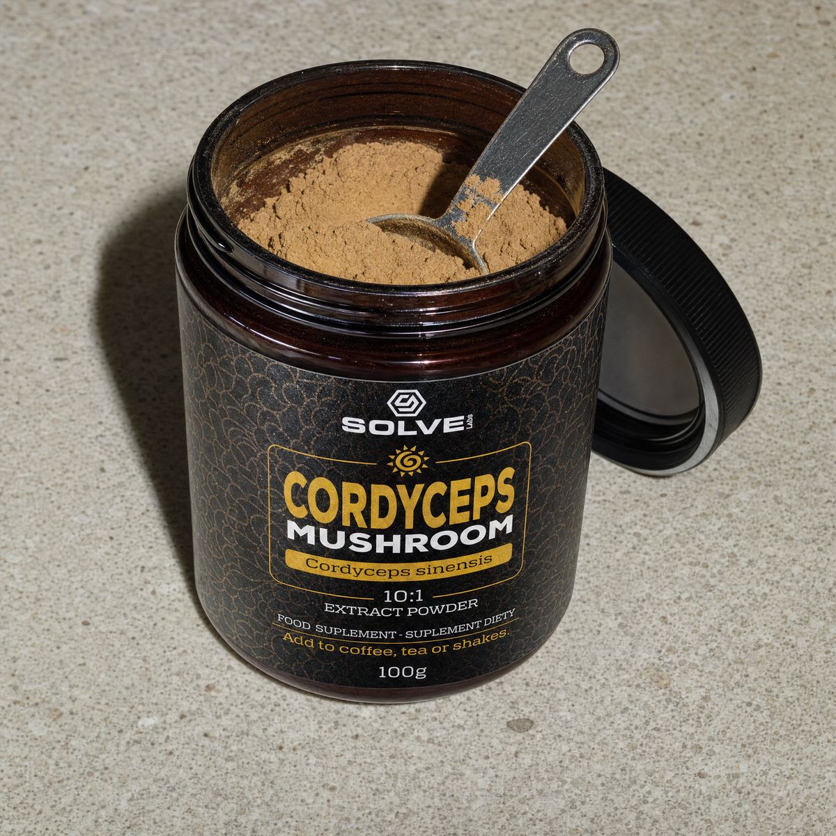 The open jar of cordyceps powder with a steel spoon in it