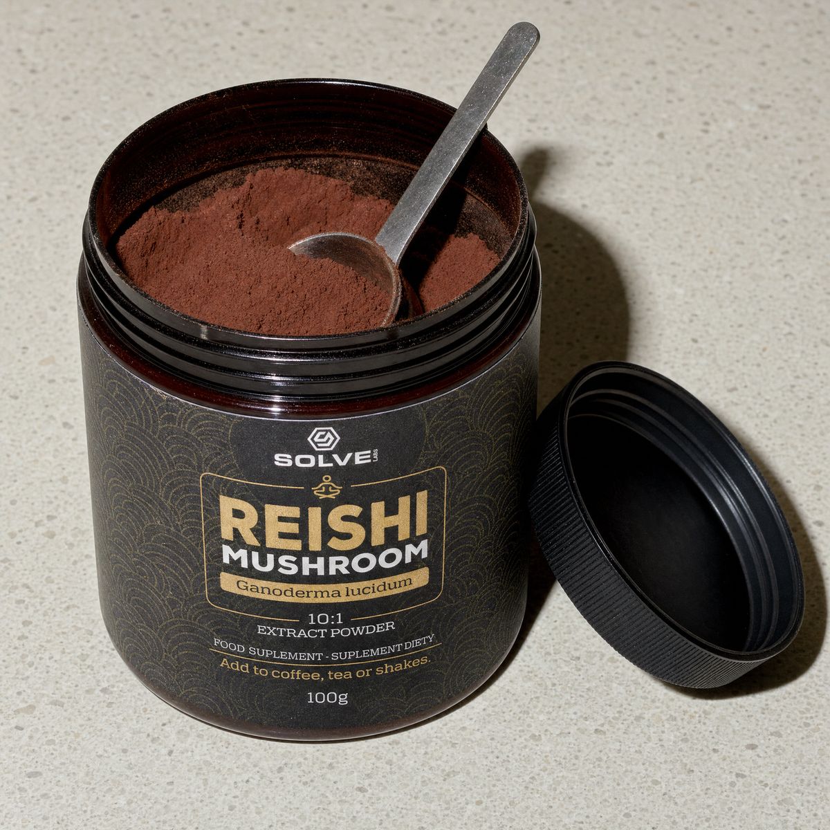 The open jar of reishi powder with a steel spoon in it