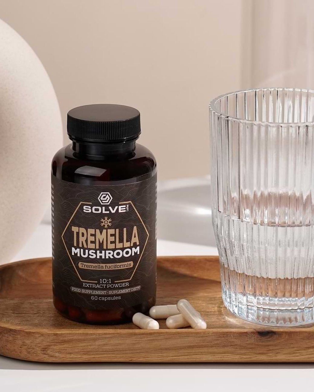 Le pot de gélules de Tremella Solve Labs sur un plateau en bois, avec des gélules et un verre d’eau