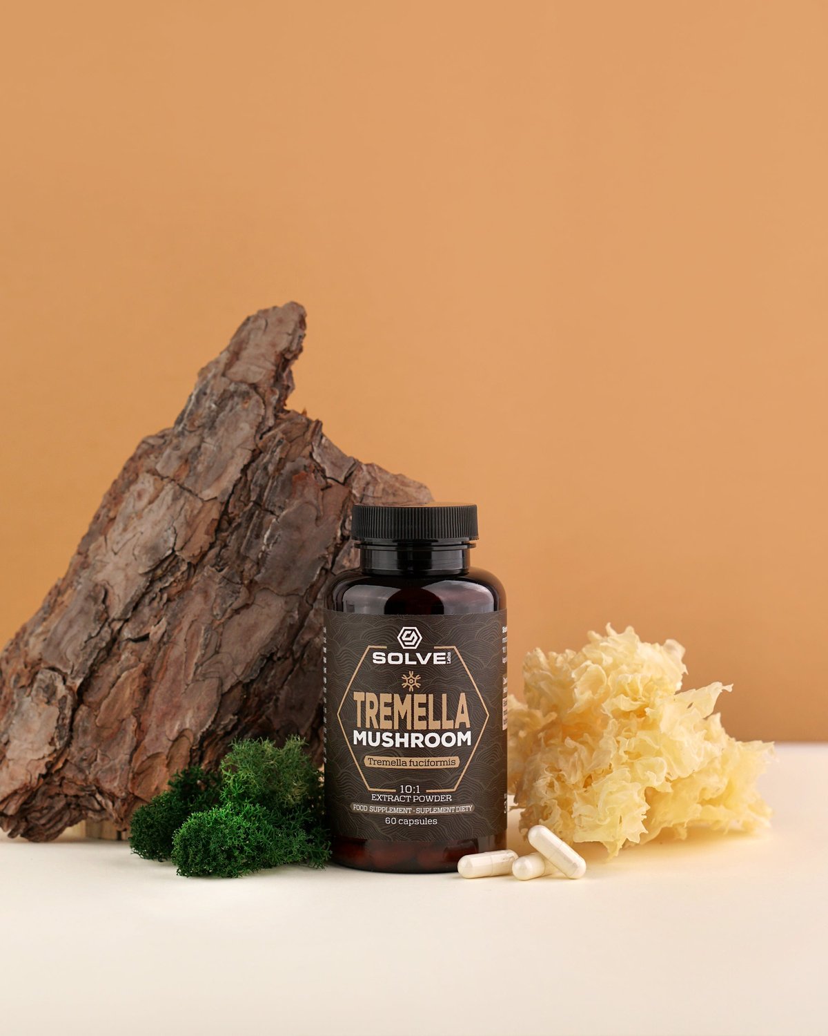 Le pot de gélules de Tremella Solve Labs entre un morceau d’écorce et un champignon des neiges séché