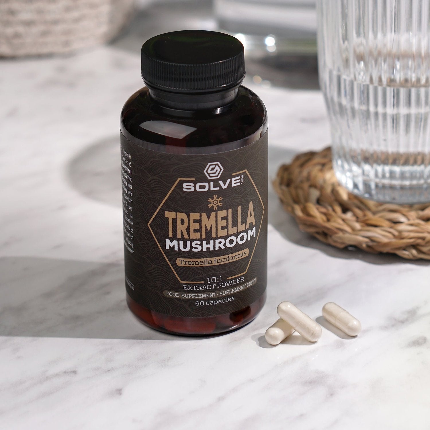 Le pot de gélules de Tremella Solve Labs sur une surface en marbre, avec trois gélules et un verre d’eau