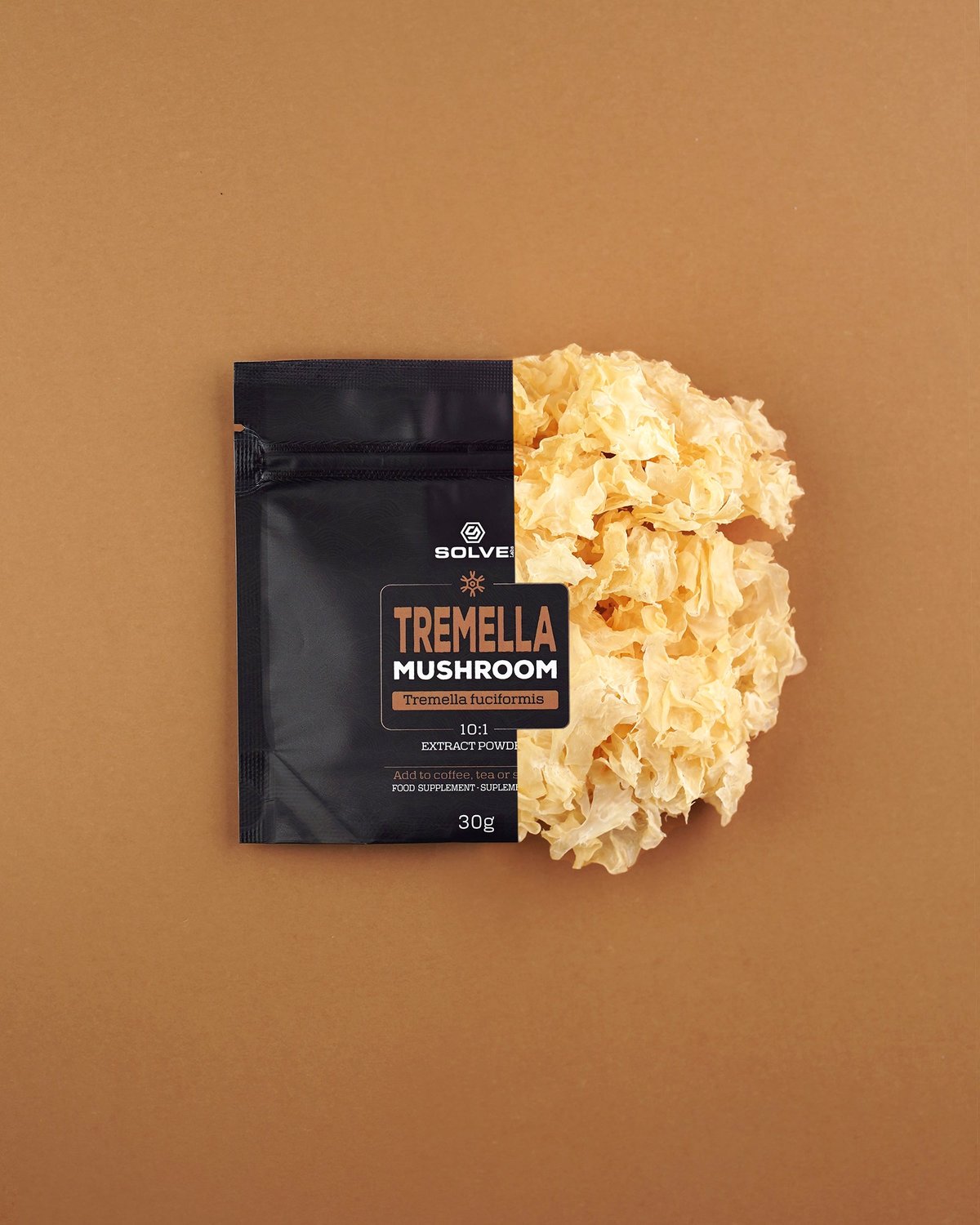 Der 30-g-Beutel Solve Labs Tremella-Pulver, quer darauf liegt ein getrockneter Schneepilz