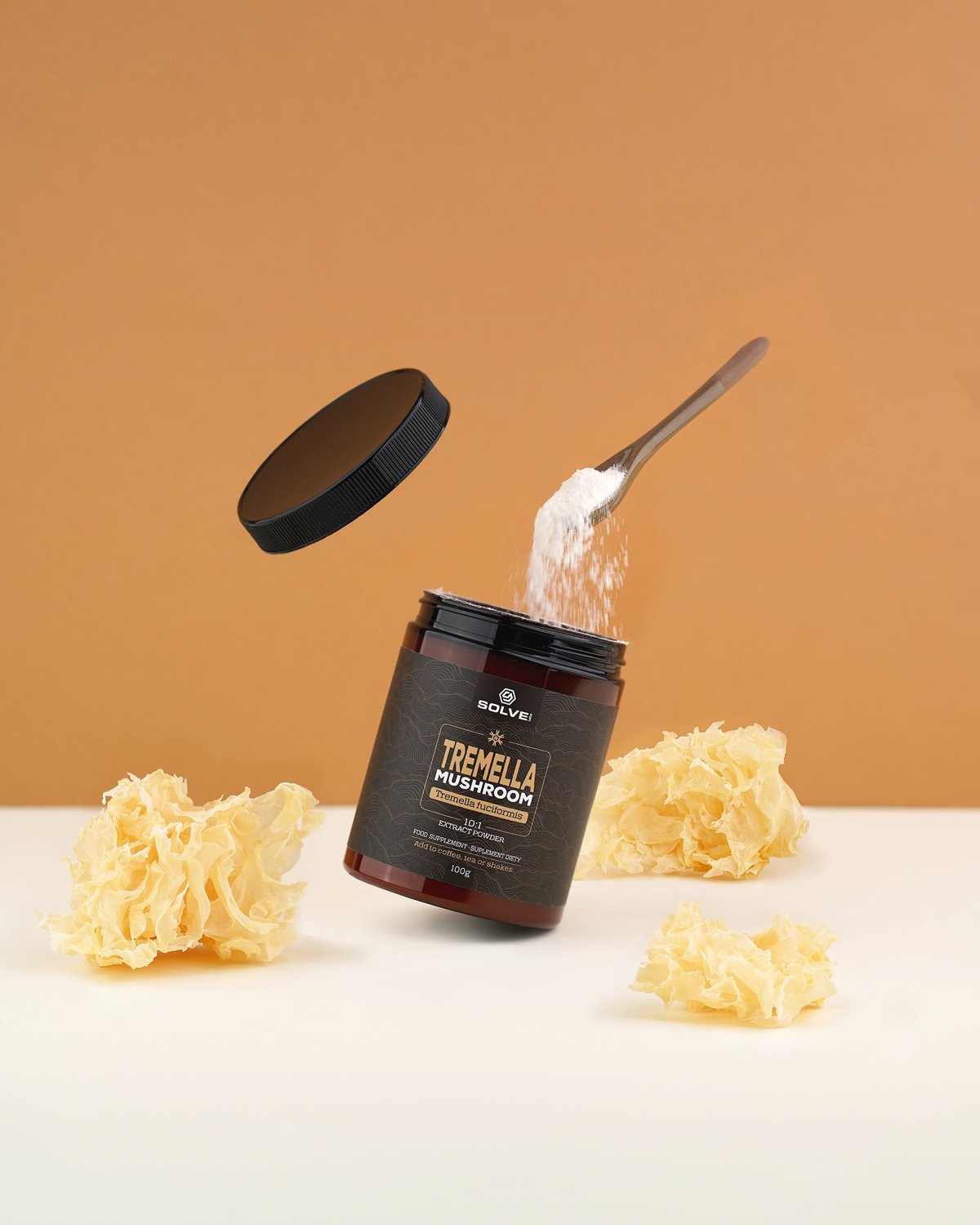 Ein Löffel weißes Tremella-Pulver wird in die offene Dose Solve Labs Tremella gekippt, ringsum getrockneter Schneepilz