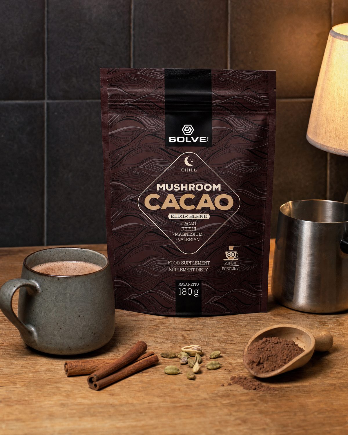 The pouch of Solve Labs Mushroom Cacao on a kitchen worktop in lamp-light with a mug of cacao, cinnamon, cardamom and a scoop of the powder