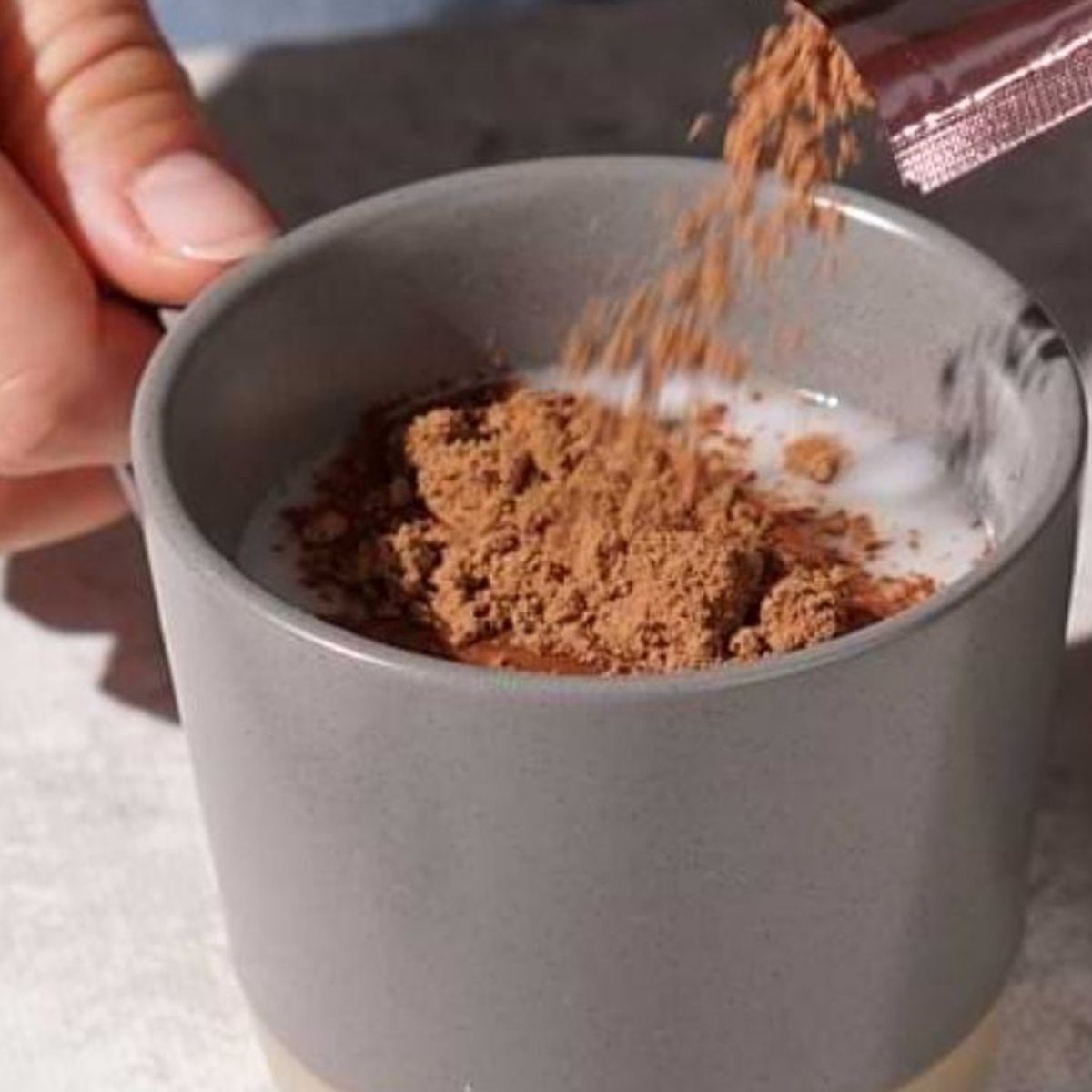 Cacao powder falling into a mug of milk