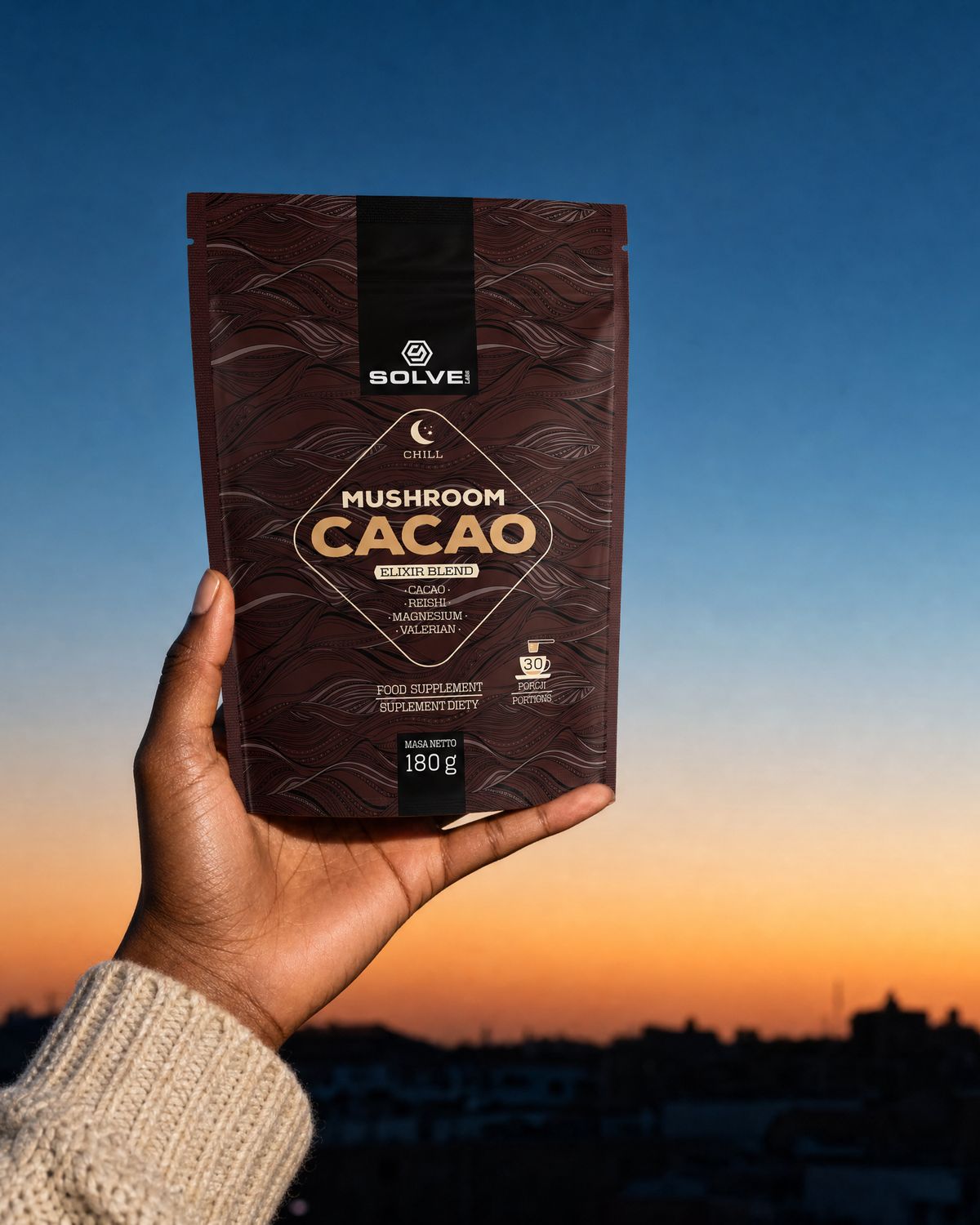 A hand holding up the pouch of Solve Labs Mushroom Cacao against an evening sky