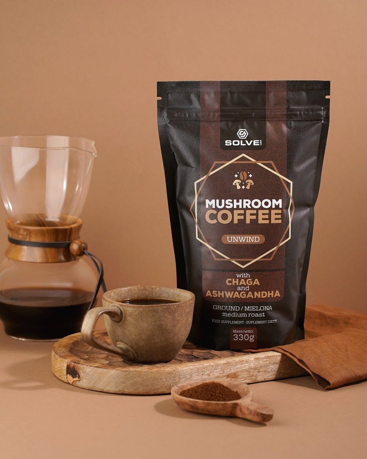 A bag of Mushroom Coffee with Chaga beside a pour-over carafe and a filled stoneware cup