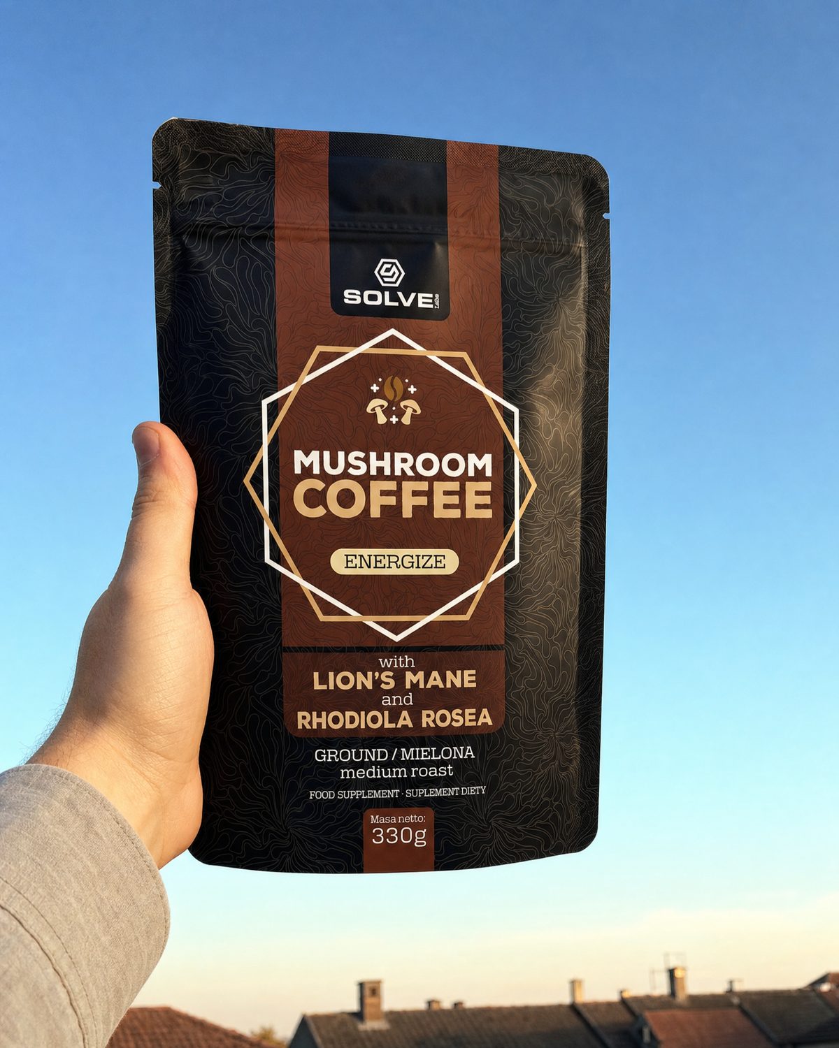 A hand holding up a bag of Solve Labs Mushroom Coffee with Lion&rsquo;s Mane against a morning sky