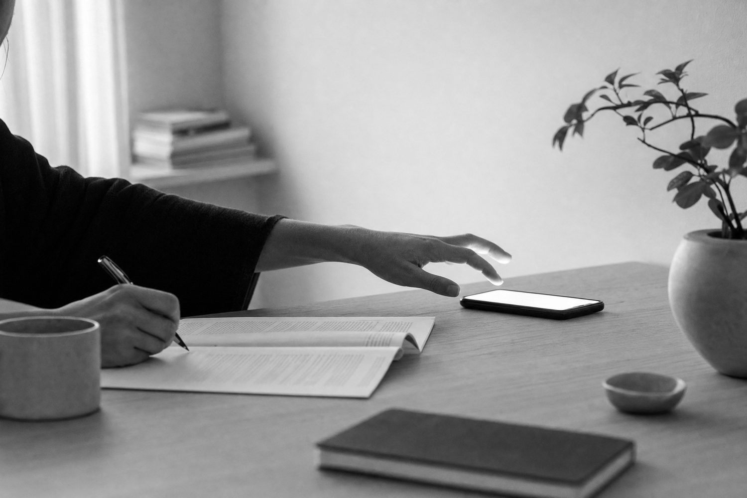 A hand leaving a page mid-sentence for a phone that has just lit up
