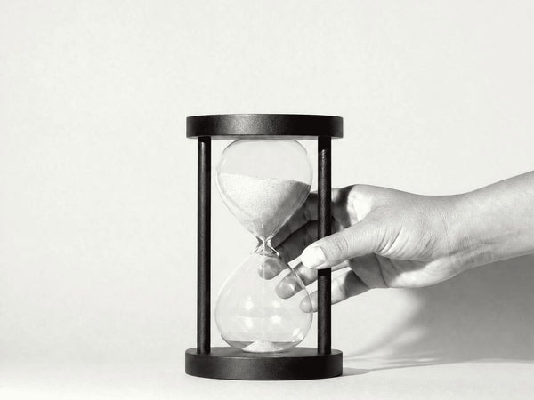 A hand setting down an hourglass