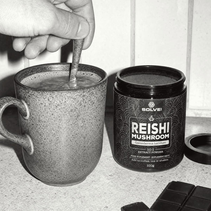 Ein Becher Kakao wird umgerührt, daneben eine Dose Reishi-Pulver