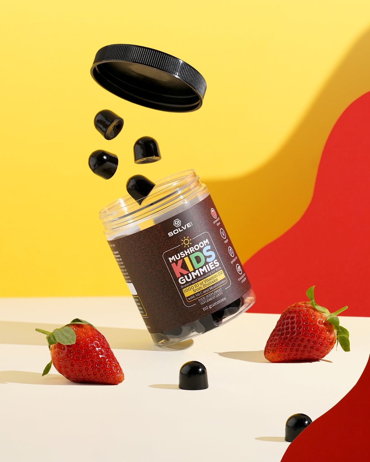 The jar of Solve Labs Mushroom Kids Gummies tipping out gummies among strawberries on a yellow backdrop