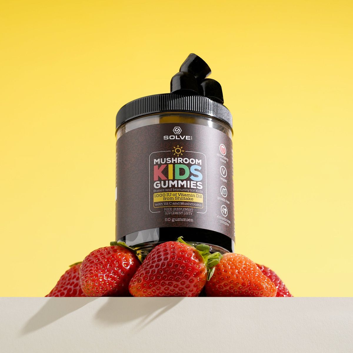 The jar of Solve Labs Mushroom Kids Gummies with strawberries on a yellow backdrop