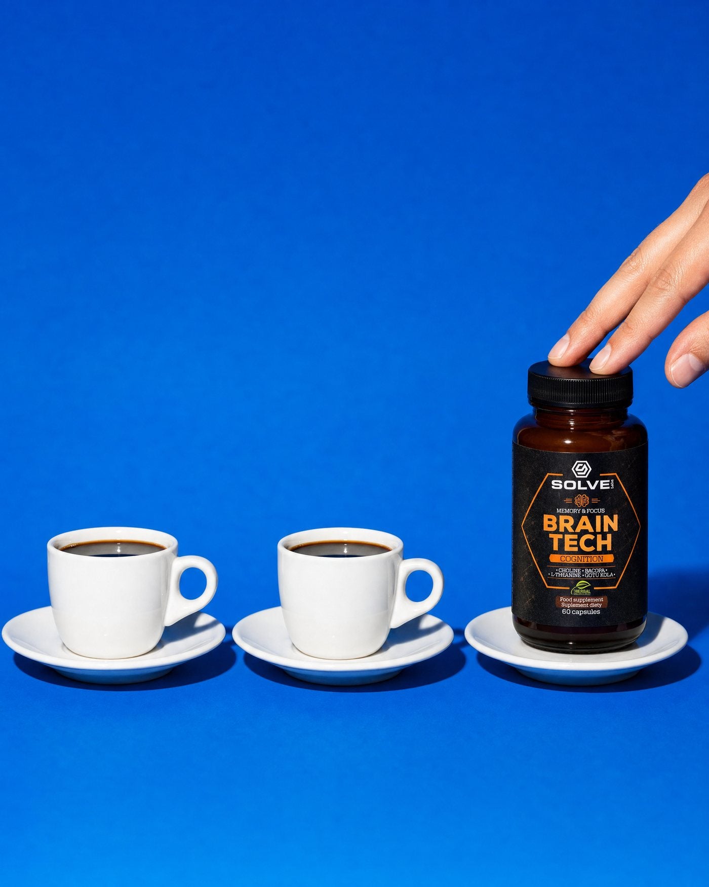 Two espresso cups of coffee in a row on a blue ground, and the Solve Labs Brain Tech jar standing where the third cup would be