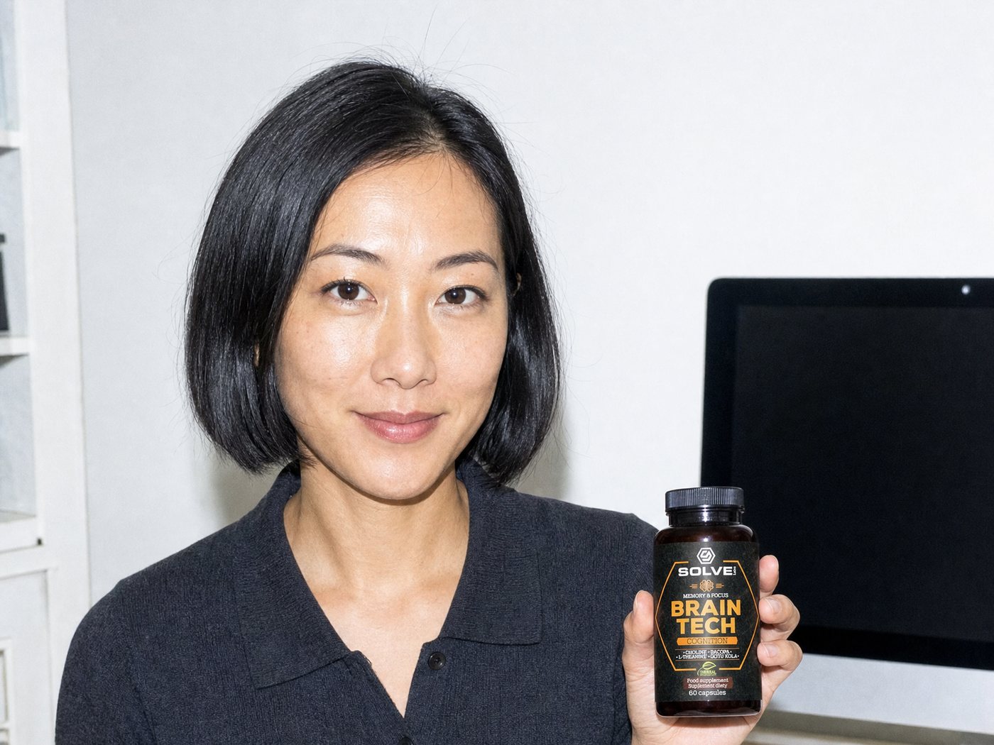 A woman at her desk with a cup of coffee in one hand and the Brain Tech jar in the other
