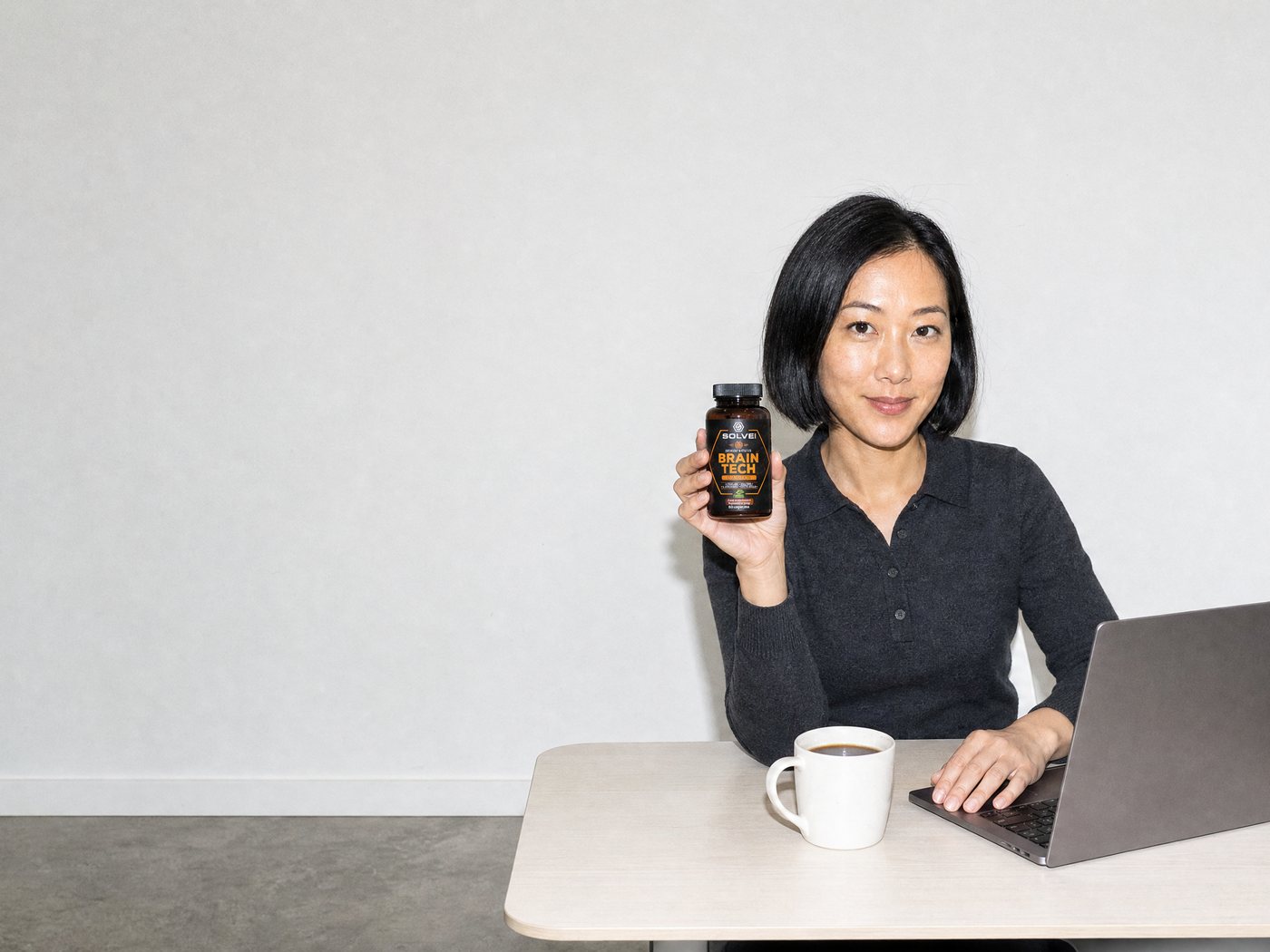 A woman working at a laptop in a bright office, the Brain Tech jar in her hand