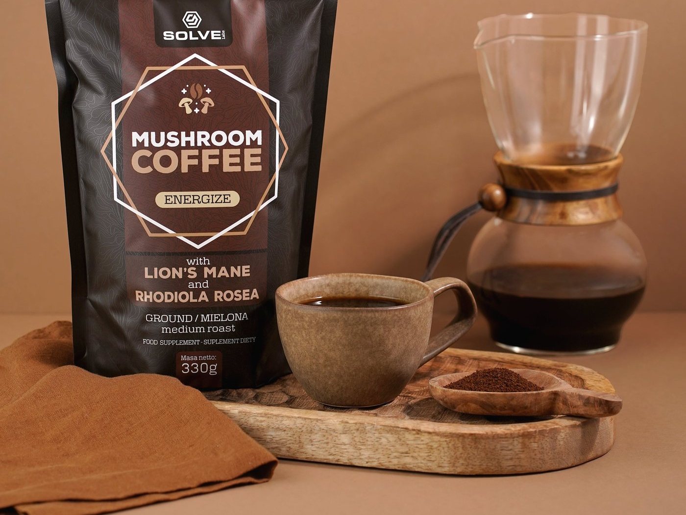The Mushroom Coffee bag beside a glass coffee maker and a ceramic cup on a wooden board