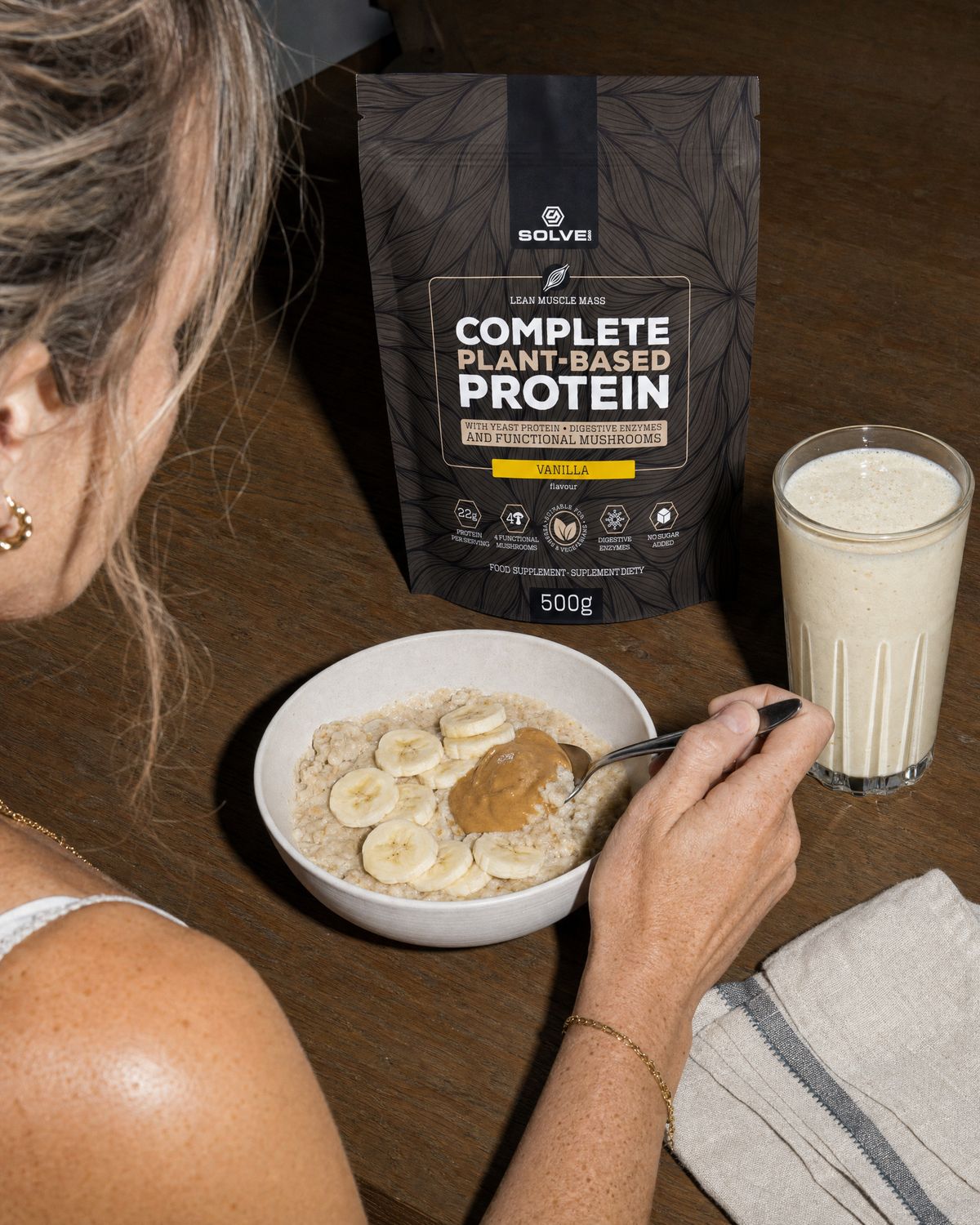A bowl of porridge with banana, a glass of vanilla shake and the vanilla pouch