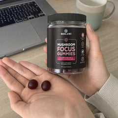 Deux Gummies Focus dans une paume ouverte à un bureau, le pot dans l’autre main