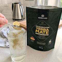 Une cuillère de Yerba maté aux champignons versée dans un verre d’eau glacée sur un plan de travail de cuisine