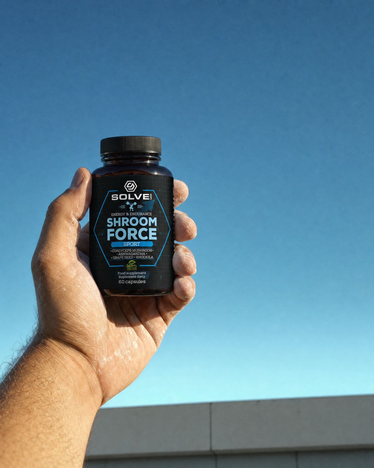 A hand holding up the jar of Solve Labs Shroom Force against a clear sky