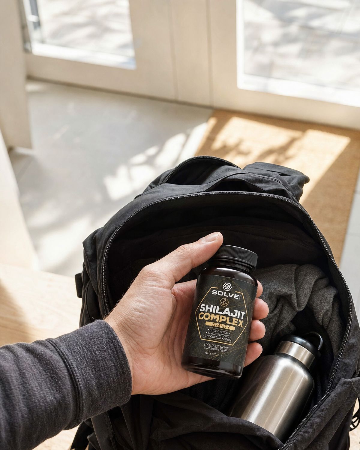 A hand dropping the jar into a black backpack with a steel water bottle in it